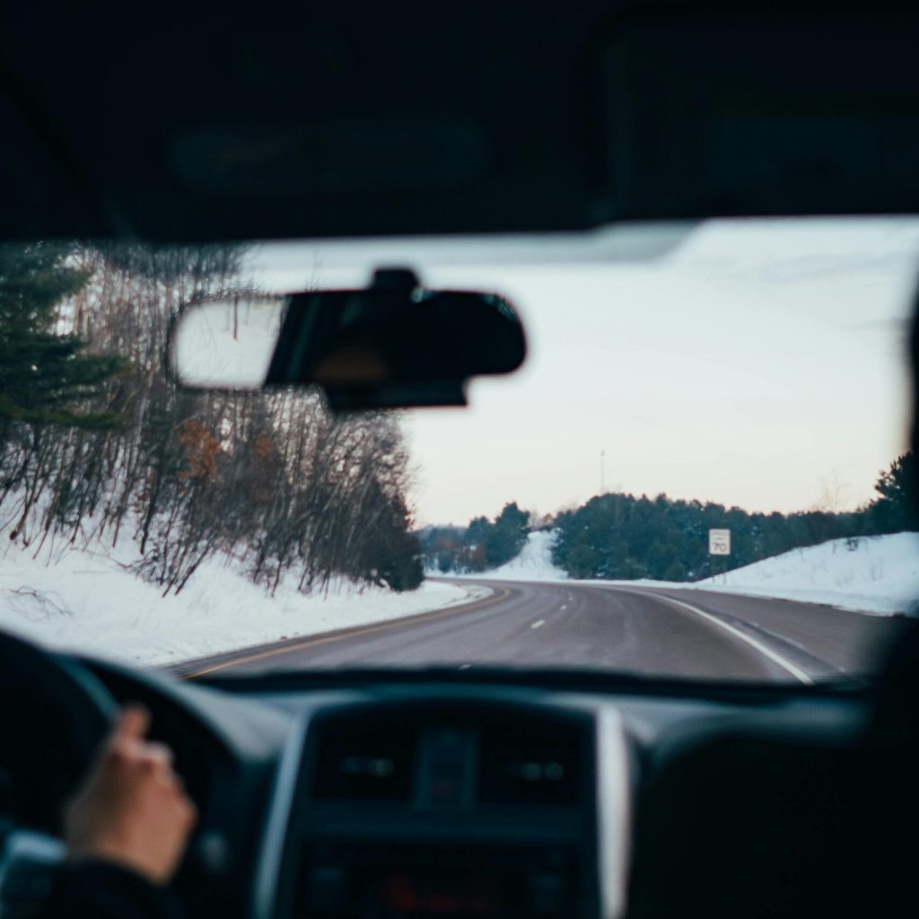 Driving along a snowy highway in winter, capturing the serene landscape and vehicle interior view.